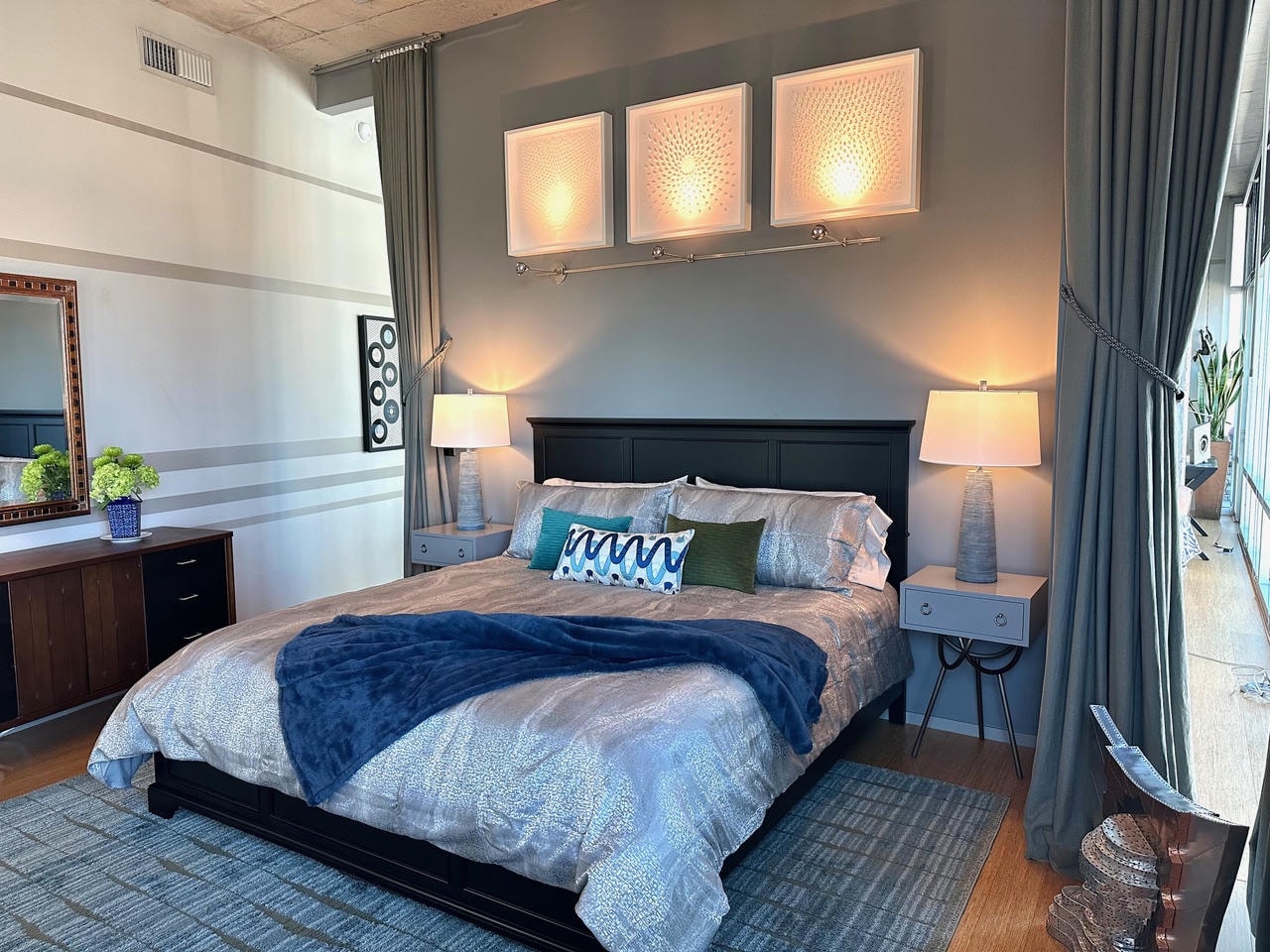 Nashville Gulch — After, master bedroom with black headboard, three illuminated wall art panels and blue accents