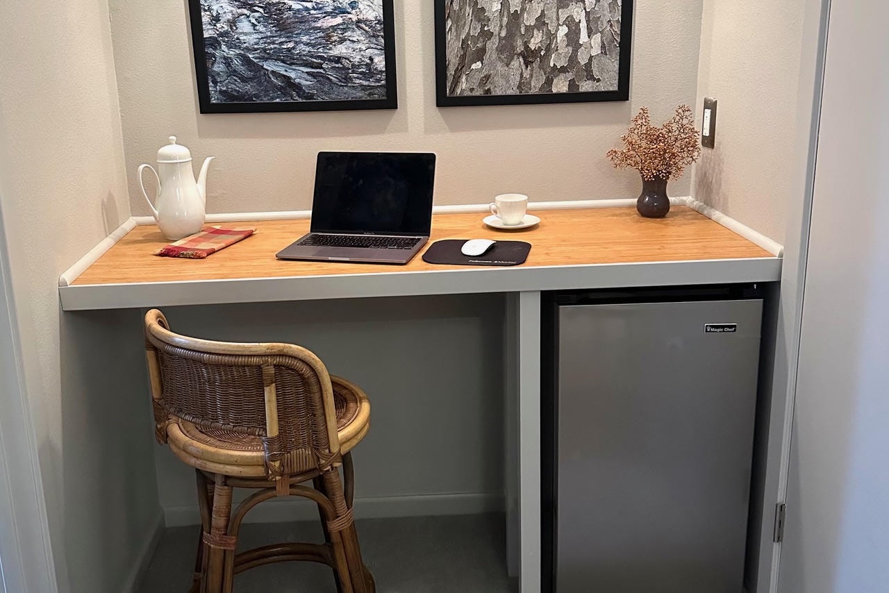 Austin Rock — After, styled workspace nook with wood desk, wicker chair, laptop and nature artwork
