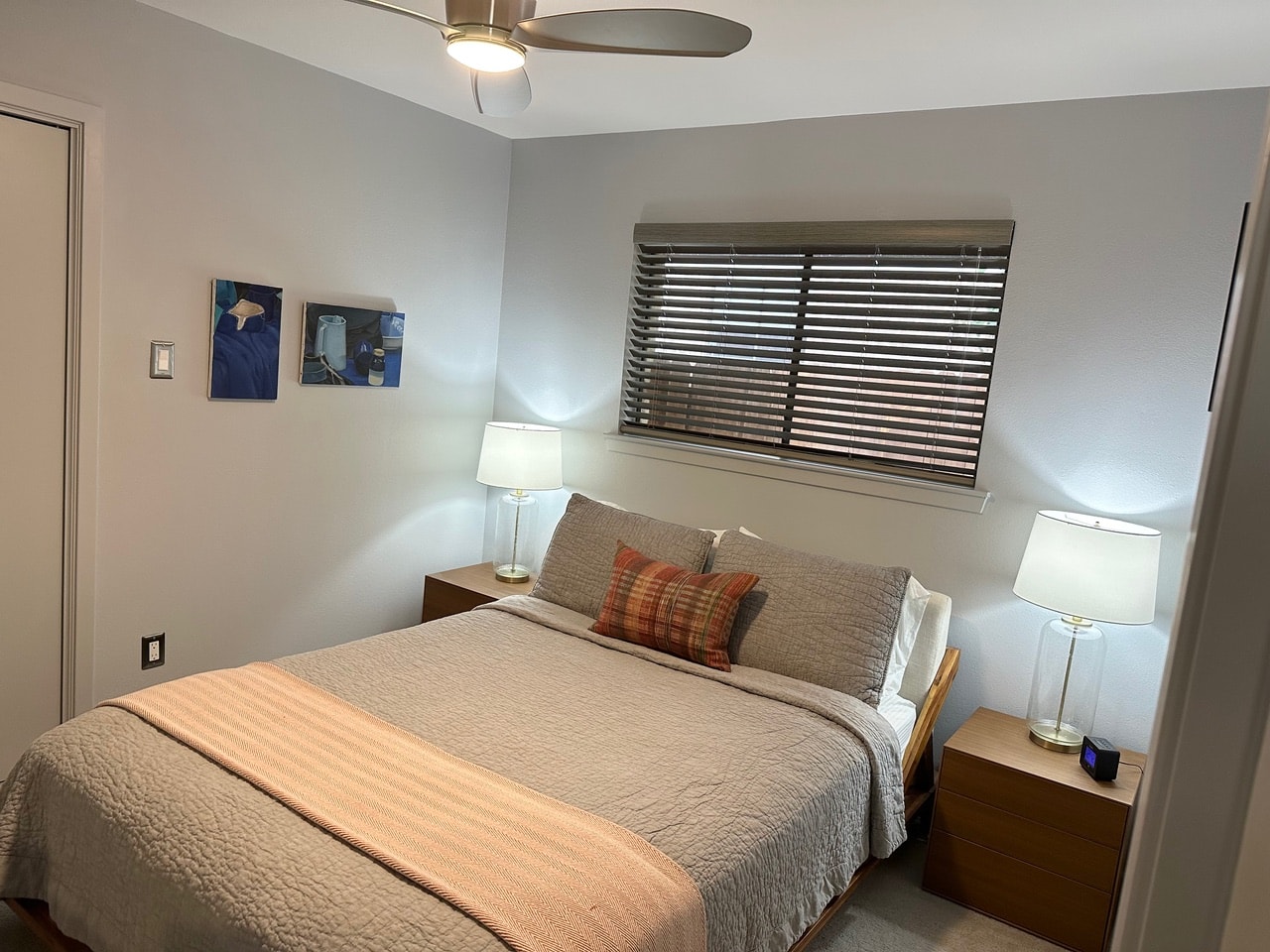 Austin Rock — After, bedroom with taupe bedding, plaid pillows, wood nightstands and blue artwork
