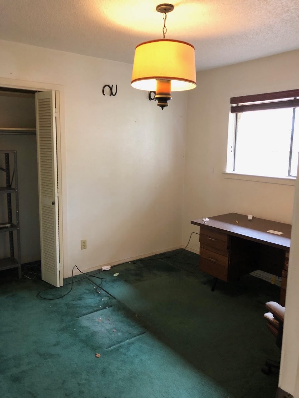 Austin Rock — Before, empty bedroom with green carpet, vintage pendant light and closet