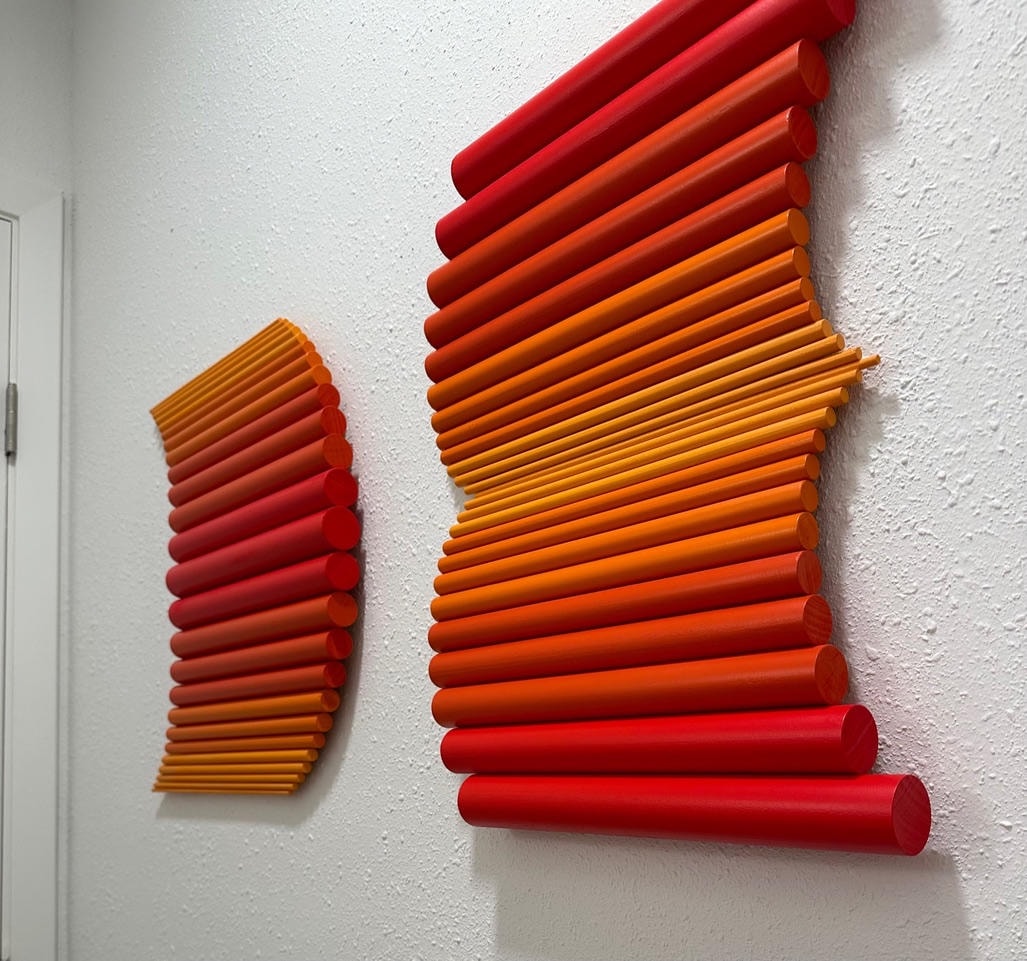 Gradient wall sculpture of cylindrical rods transitioning from red to orange to yellow