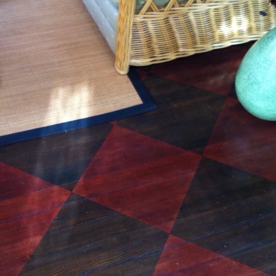 Decorative painted wood floor with red and black diamond pattern, wicker furniture and turquoise accents