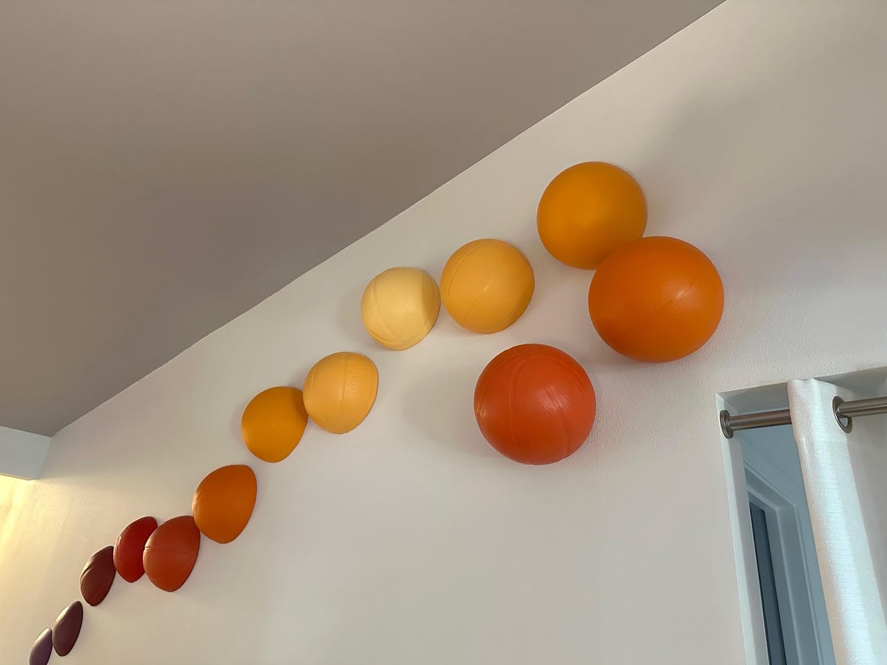 Gradient wall installation of spherical objects in warm orange and red tones