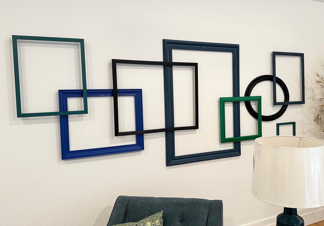 Overlapping empty frames in teal, blue, black and green arranged as wall sculpture