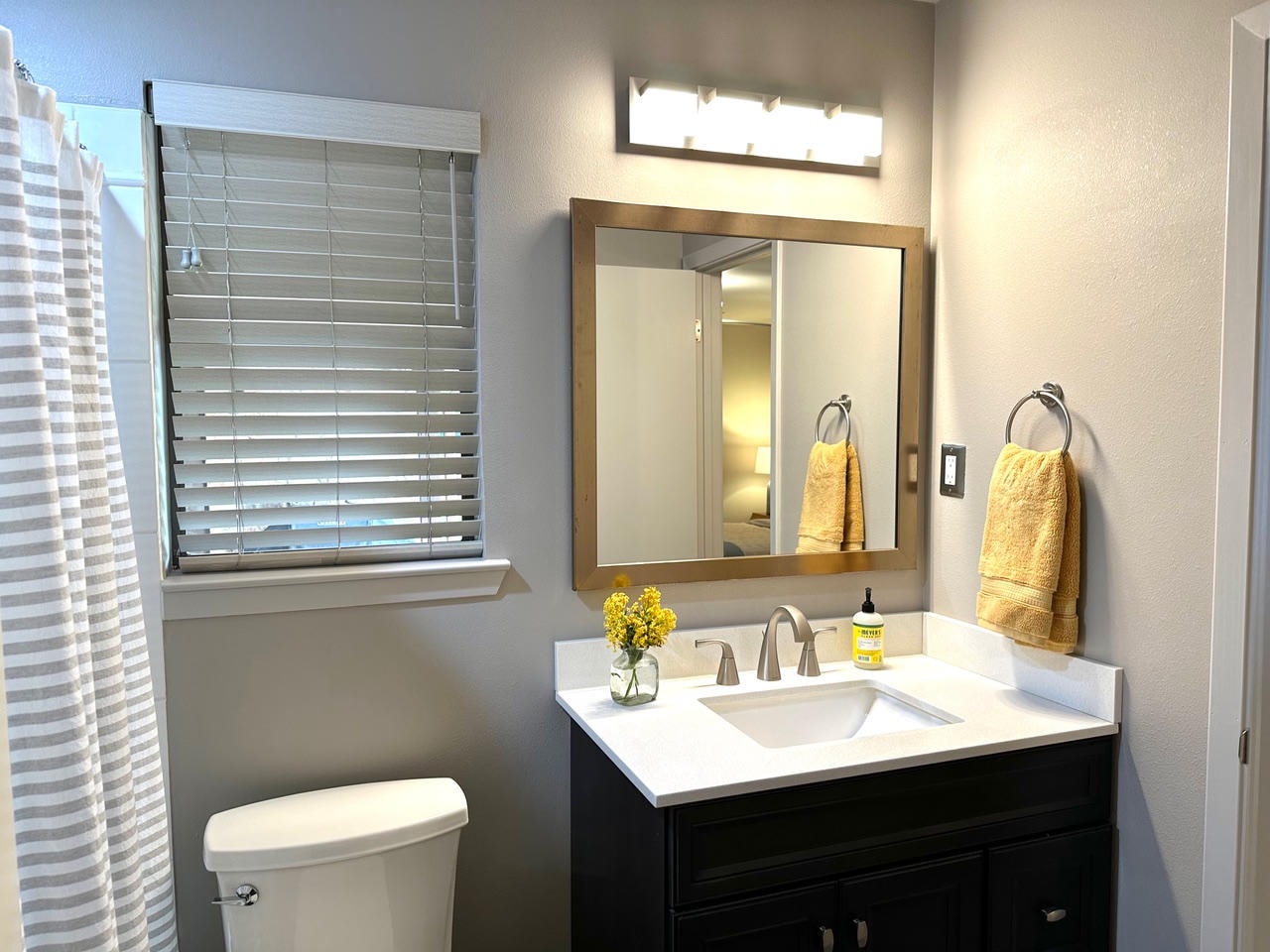 Austin Rock — After, bathroom with dark vanity, wood-framed mirror and yellow accents