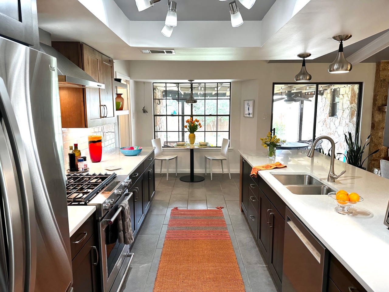 Austin Rock — After, renovated kitchen with dark cabinets, white countertops and orange runner rug