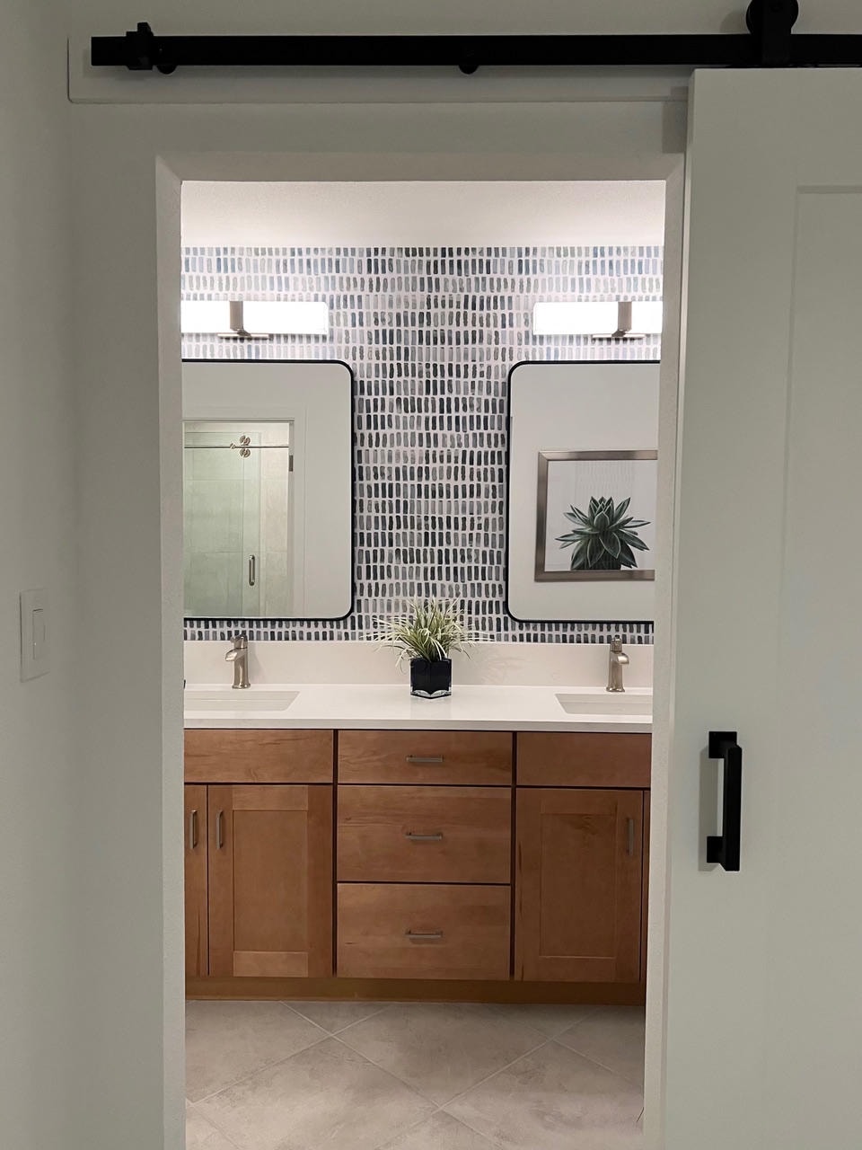 Austin Trail — After, bathroom with wood vanity and patterned tile backsplash viewed through barn door