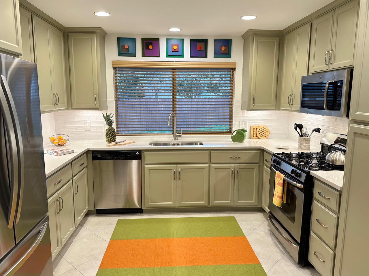 Austin Trail — After, kitchen with sage green cabinets, colorful art and striped rug, wide view