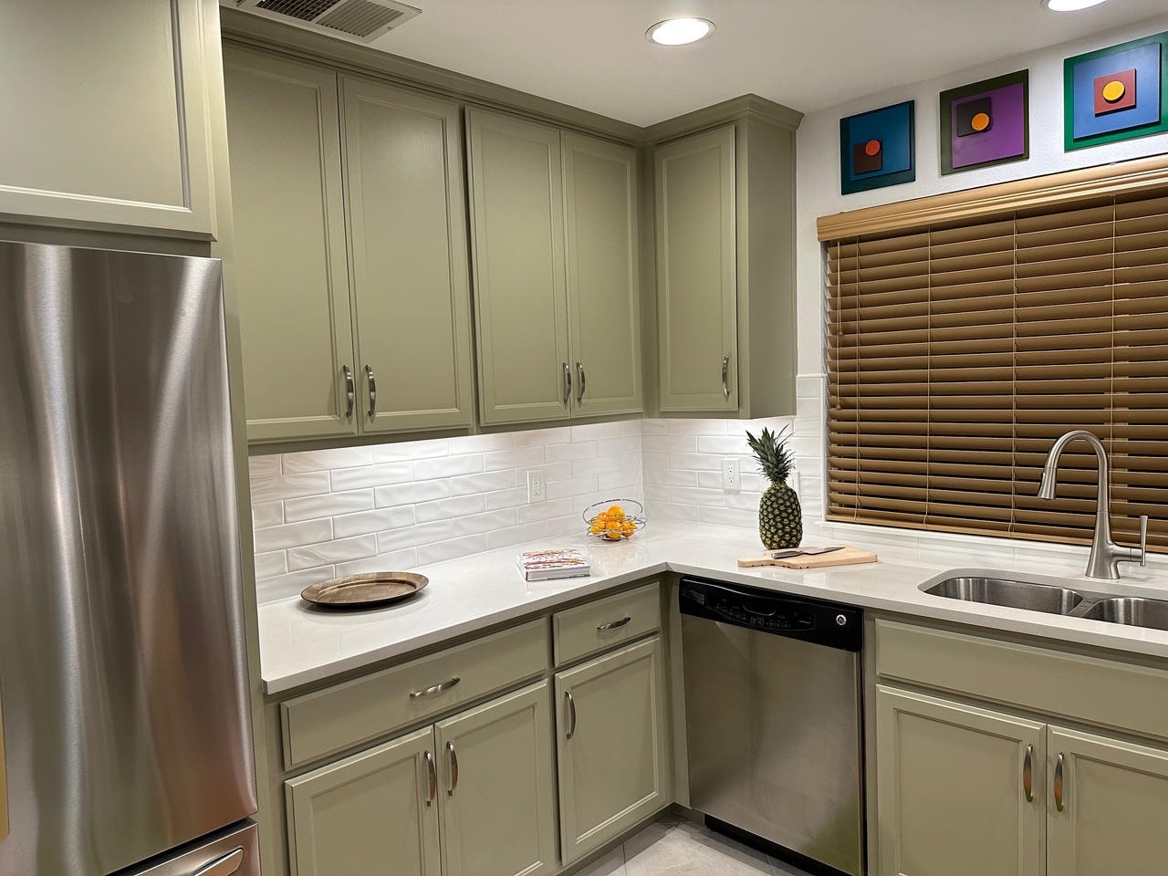 Austin Trail — After, kitchen with sage green cabinets and colorful art, side angle