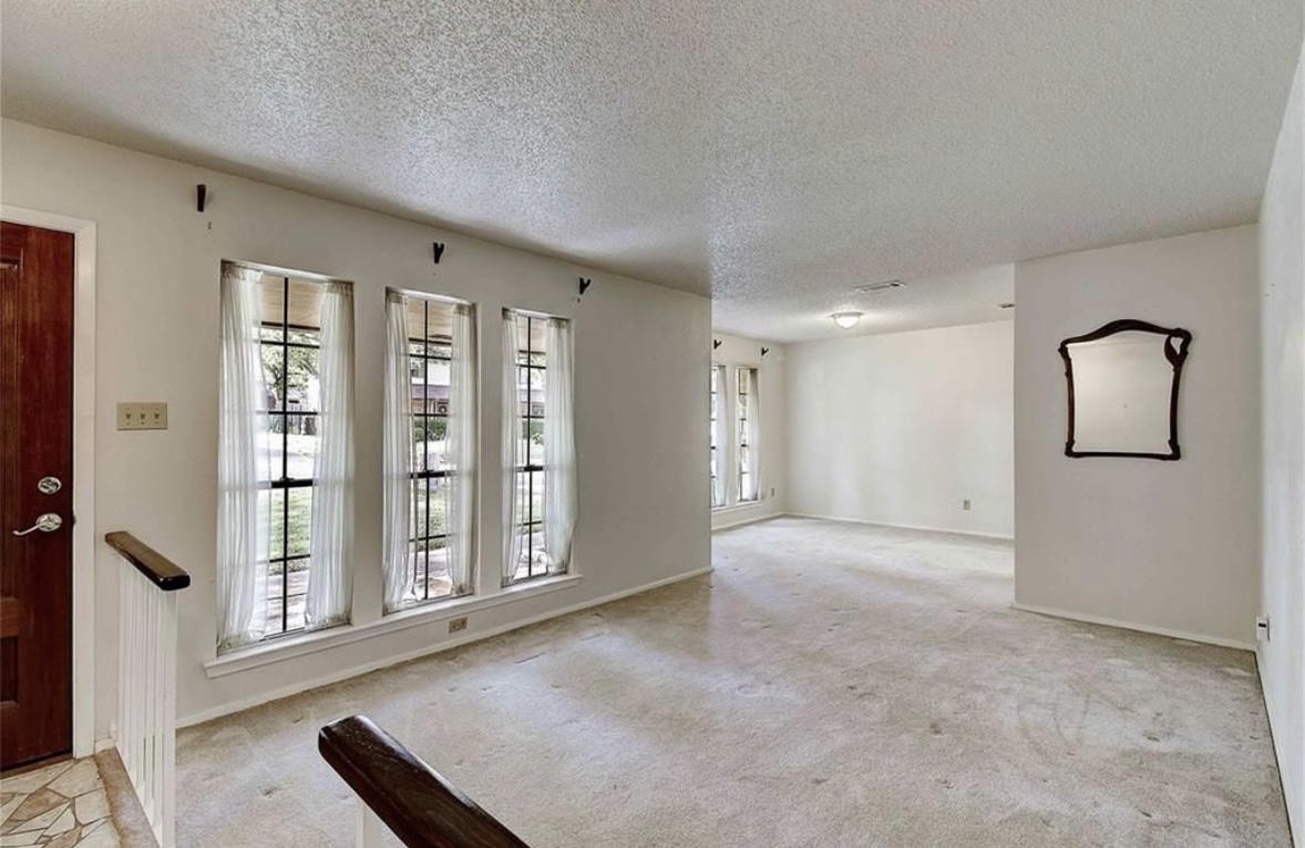Austin Rock — Before, empty living room with large windows and carpet, angle 1