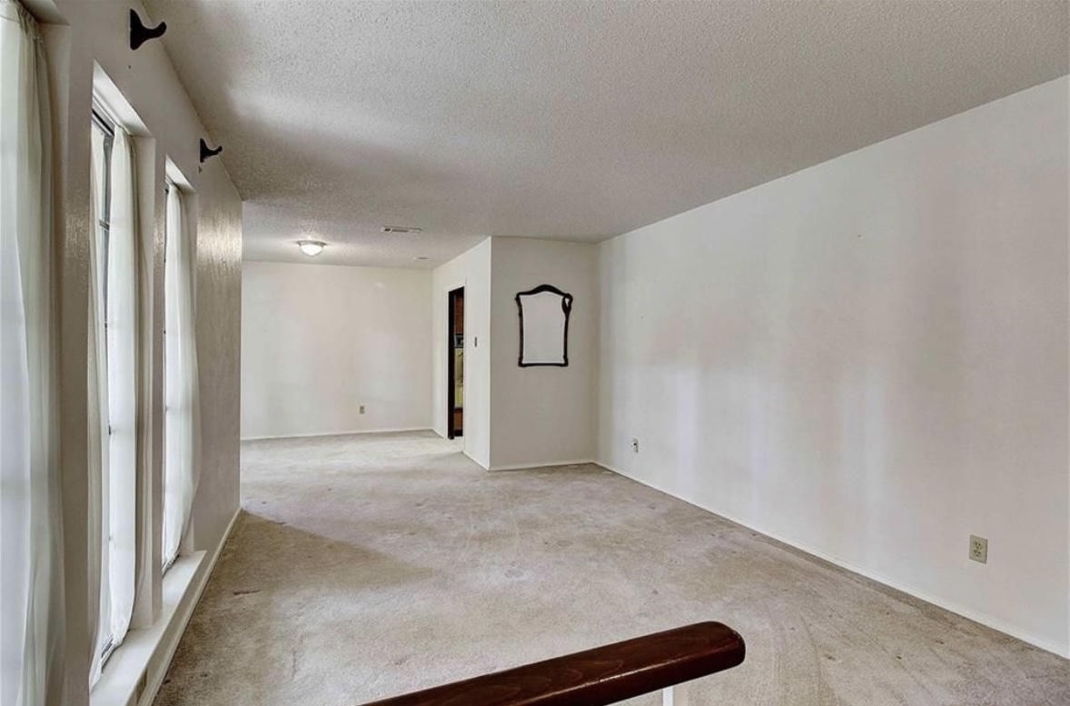 Austin Rock — Before, empty living room with large windows and carpet, angle 2